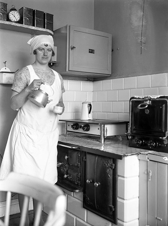 Hembiträdet Gunhild häller upp kaffe i köket