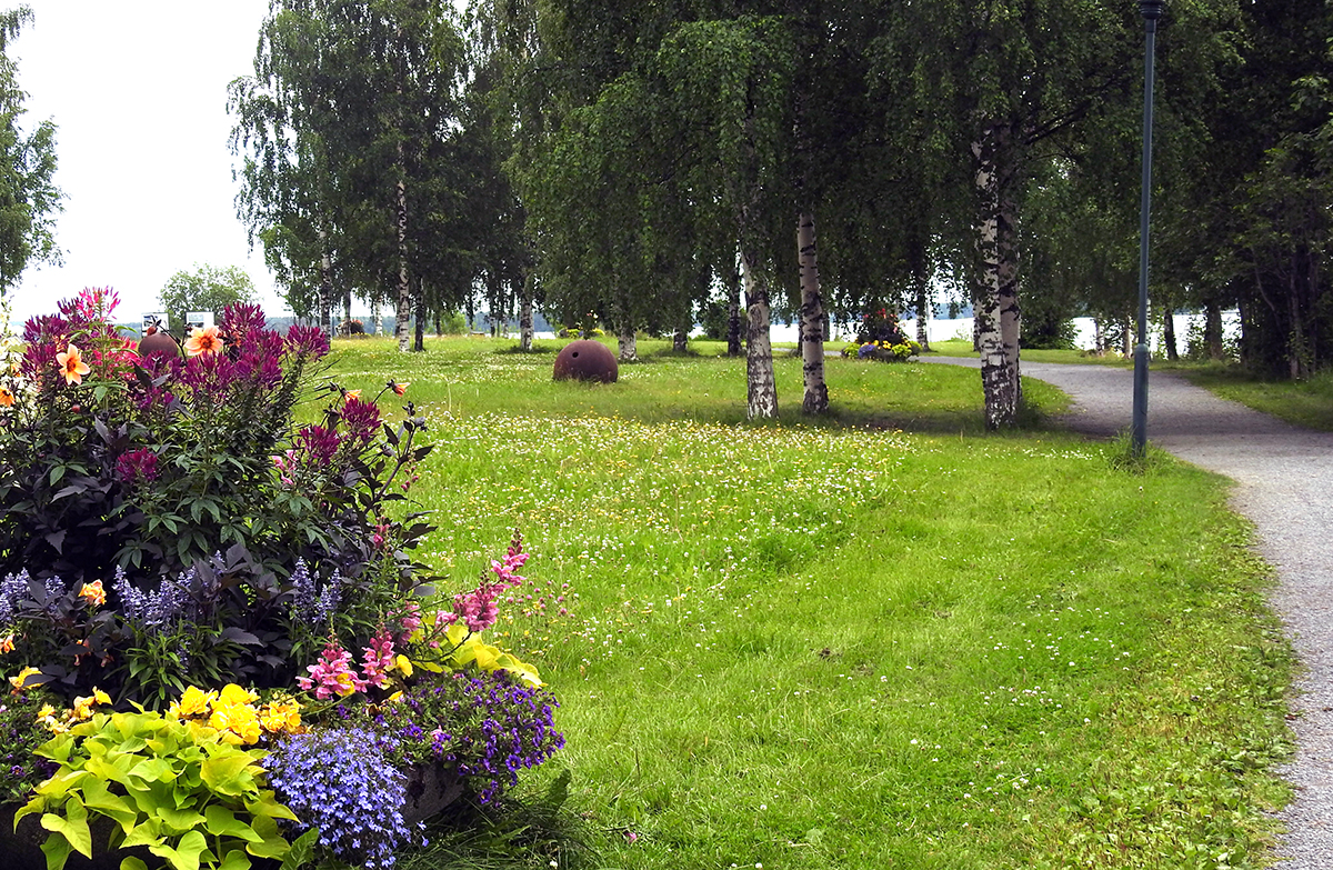 Blomplantering i förgrunden och gång- och cykelväg till höger som slingrar sig efter stranden